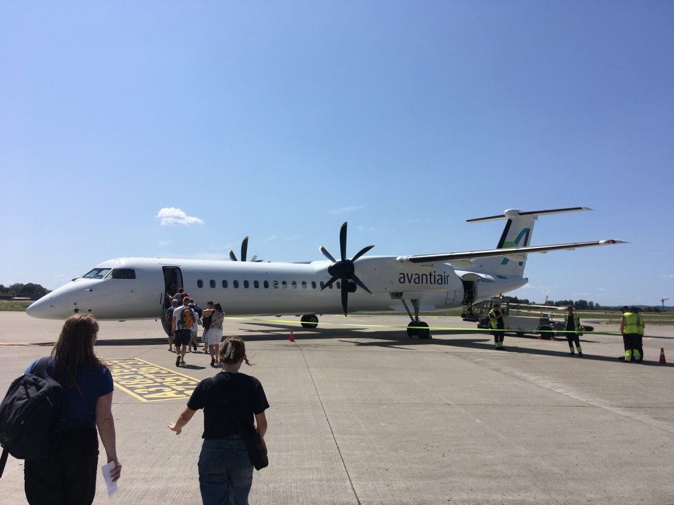 Dash 8 turboprob aircraft on apron with passengers boarding